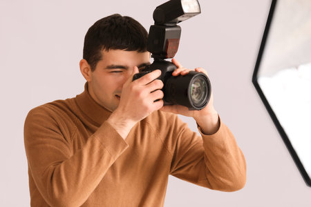 Young male photographer with professional camera in studio, closeup