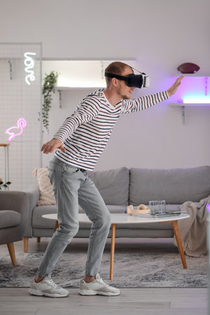 Young man using VR glasses at homeの写真素材