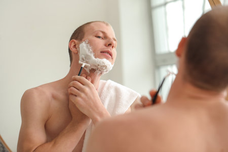 Young man shaving in the bathroomの写真素材