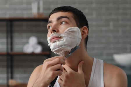 Young man shaving in the bathroomの写真素材