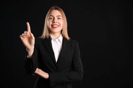 Female business consultant using virtual screen on black backgroundの写真素材