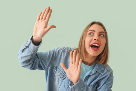 Surprised young woman in denim shirt on green backgroundの写真素材