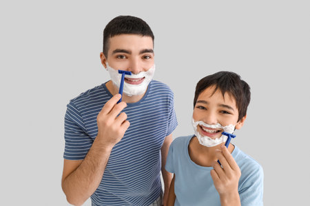 Father and his little son shaving against light backgroundの写真素材