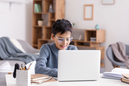 Little boy in eyeglasses using laptop at home