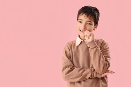 Little boy biting nails on pink backgroundの写真素材