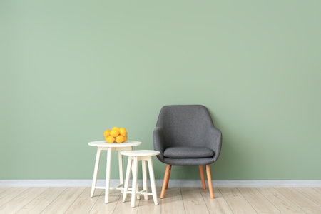 Stylish armchair with tables and lemon fruit near color wall in living roomの写真素材