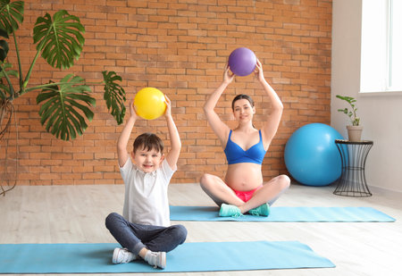 Beautiful pregnant woman with her little son training in gymの写真素材