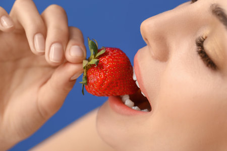 Sexy young woman with strawberry on color background, closeupの写真素材