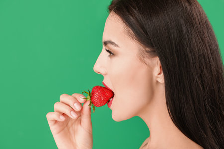 Sexy young woman with strawberry on color backgroundの写真素材