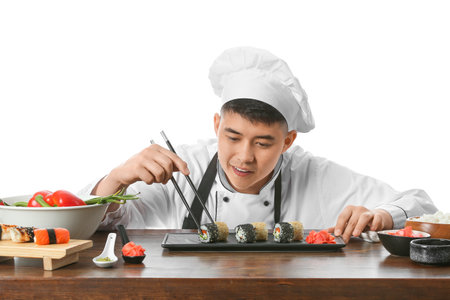 Handsome Asian chef with sushi rolls on white backgroundの写真素材