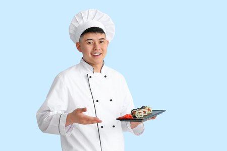 Handsome Asian chef with sushi rolls on color backgroundの写真素材