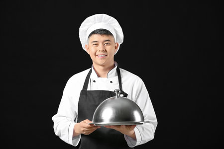 Handsome Asian chef with tray on dark backgroundの写真素材