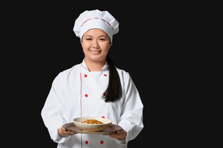 Beautiful Asian chef with dish on dark backgroundの写真素材