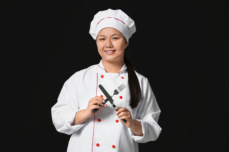 Beautiful Asian chef with cutlery on dark backgroundの写真素材
