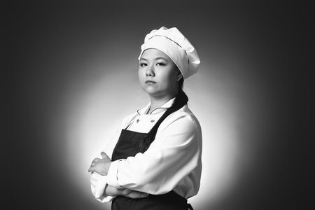 Toned portrait with beautiful Asian chef on dark backgroundの写真素材