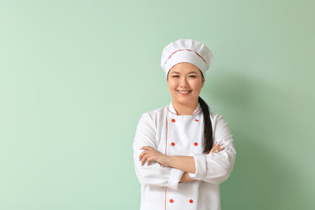 Beautiful Asian chef on color backgroundの写真素材