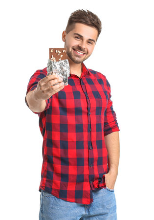 Handsome young man with tasty chocolate on white backgroundの写真素材