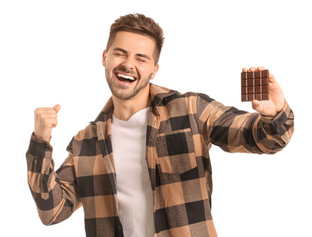 Happy young man with tasty chocolate on white backgroundの写真素材