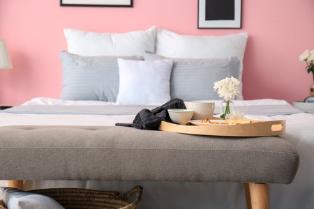 Tray with breakfast on bedside bench in interior of modern roomの写真素材