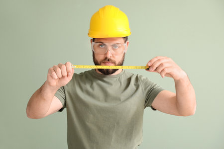 Male worker with tape measure on color backgroundの写真素材