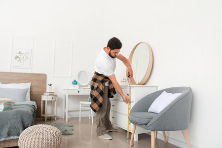 Male carpenter using tape measure in roomの写真素材