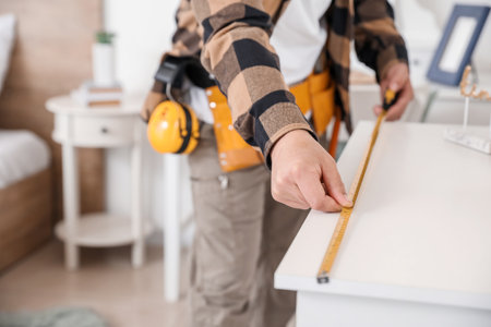Male carpenter using tape measure in room, closeupの写真素材