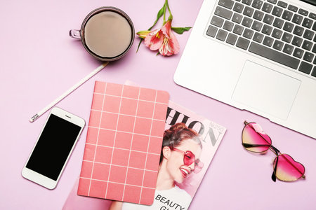 Laptop with mobile phone, stationery and cup of coffee on color backgroundの写真素材