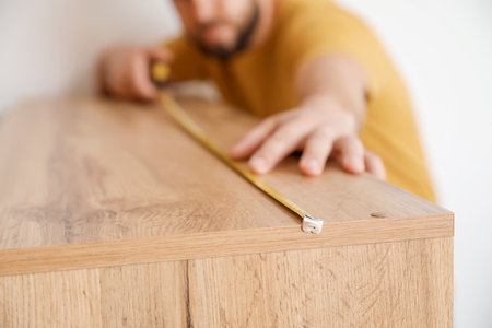 Male carpenter using tape measure in room, closeupの写真素材