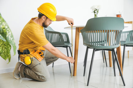 Male carpenter using tape measure in roomの写真素材