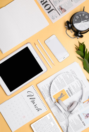 Modern devices with stationery, calendar and newspapers on color backgroundの写真素材