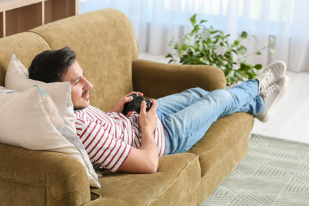 Handsome young man playing video game at homeの写真素材