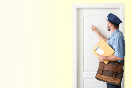 Handsome young postman knocking at the doorの写真素材