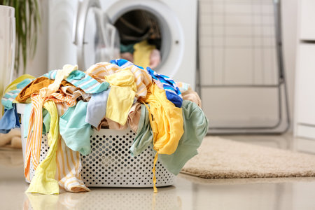 Basket with dirty clothes on floor in laundry roomの写真素材