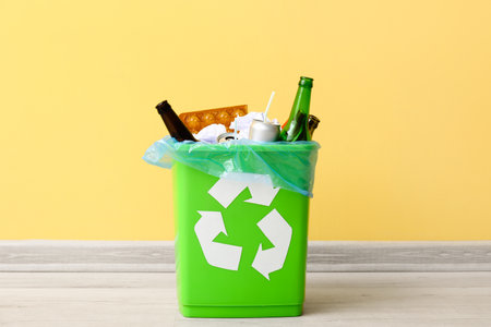 Recycling bin with garbage near yellow wallの写真素材