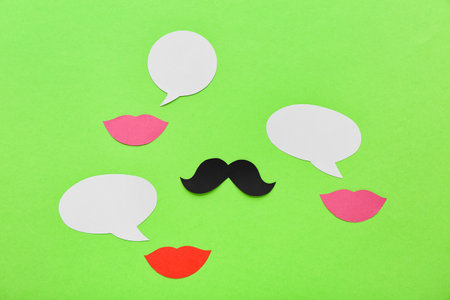 Paper lips and mustache with speech bubbles on green background. Dialogue conceptの写真素材