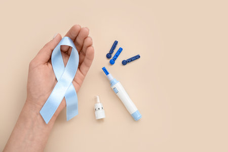 Woman with awareness ribbon, lancet pen and strips on beige background. Diabetes conceptの写真素材