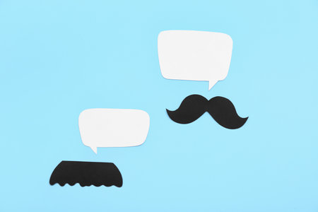 Paper mustaches with speech bubbles on blue background. Dialogue conceptの写真素材