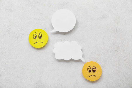 Paper faces with speech bubbles on white background. Dialogue concept