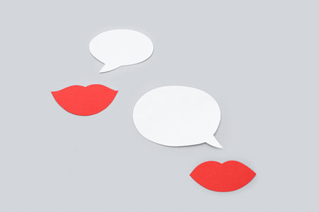 Paper lips with speech bubbles on gray background. Dialogue concept