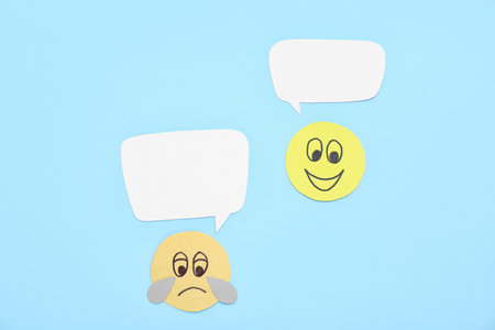 Paper faces with speech bubbles on blue background. Dialogue conceptの写真素材