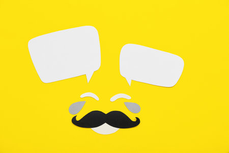 Paper male face with speech bubbles on yellow background. Dialogue conceptの写真素材