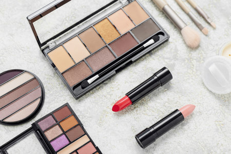 Eye shadows with lipsticks and brushes on grunge background