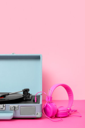 Record player with vinyl disk and headphones on table near pink wallの写真素材