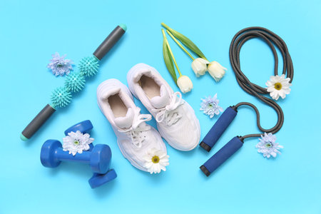 Sneakers with spring flowers and sports equipment on blue backgroundの写真素材