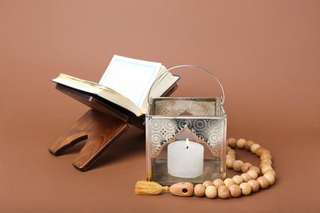 Muslim lamp with prayer beads and Koran on brown background