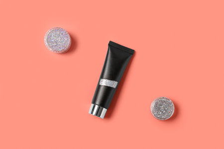 Tube with jars of silver glitter on pink backgroundの写真素材