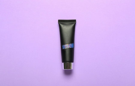Tube of glitter on lilac background