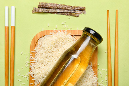 Composition with bottle of vinegar, rice, nori sheet and chopsticks on color background, closeupの写真素材