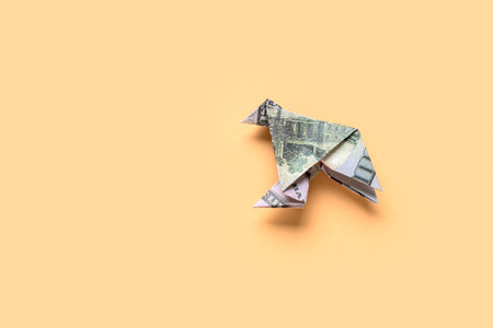 Origami bird made of dollar banknotes on beige backgroundの写真素材