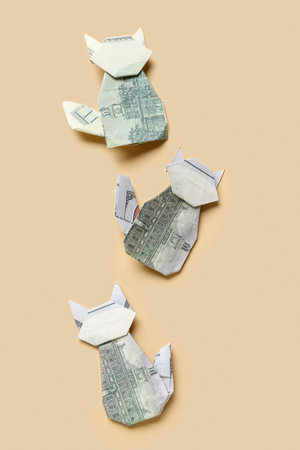 Origami cats made of dollar banknotes on beige backgroundの写真素材